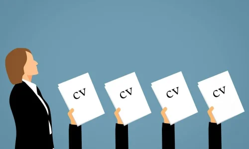 Hands lifting up CV's whilst recruiter walks past symbolizing competition in the amount of job seekers
